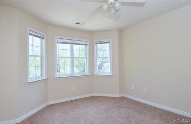 carpeted spare room with ceiling fan, visible vents, and baseboards