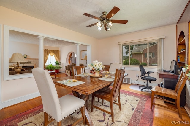dining space featuring a ceiling fan, visible vents, baseboards, ornate columns, and light wood-style flooring