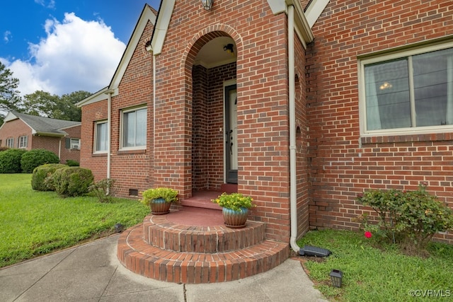 doorway to property with a yard, crawl space, and brick siding