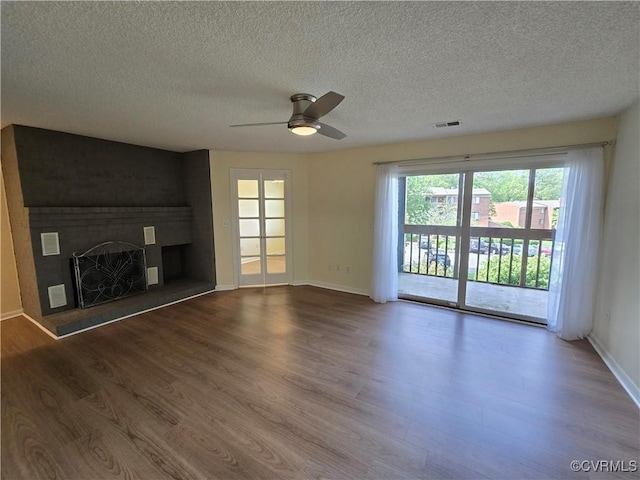 unfurnished living room featuring a large fireplace, ceiling fan, a textured ceiling, and visible vents