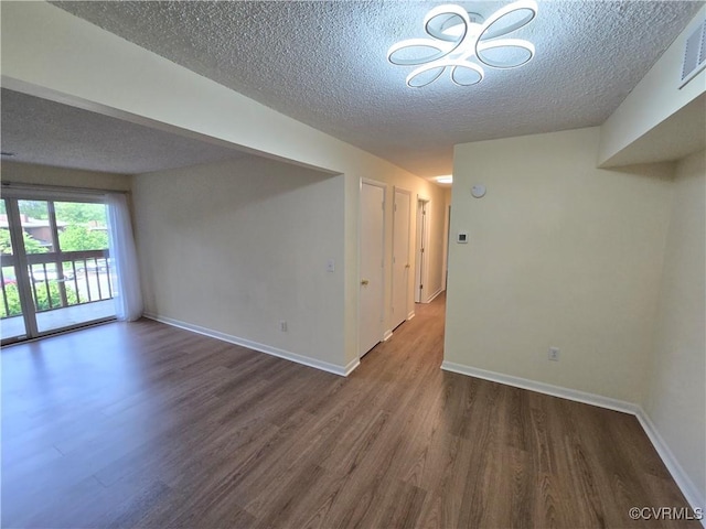unfurnished room with an inviting chandelier, baseboards, a textured ceiling, and wood finished floors