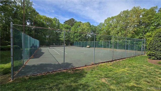 view of tennis court with fence and a lawn