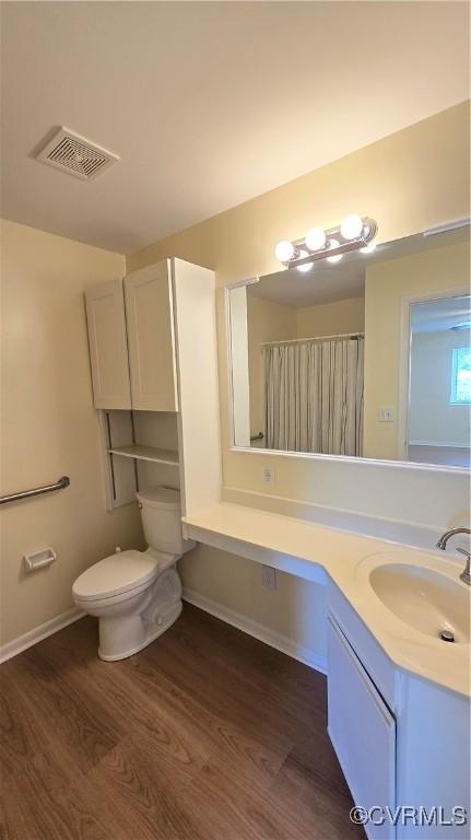 bathroom featuring visible vents, wood finished floors, vanity, baseboards, and toilet