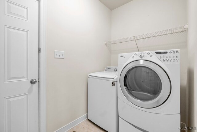 laundry room featuring washer and clothes dryer, baseboards, and light tile patterned floors