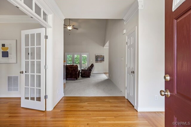 entrance foyer with ceiling fan, light wood-type flooring, baseboards, ornamental molding, and vaulted ceiling