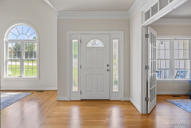 foyer entrance featuring light wood finished floors, crown molding, baseboards, and french doors