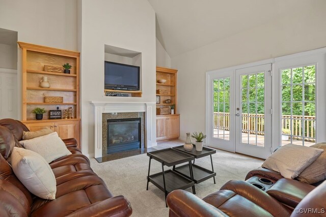 living area featuring light carpet, built in shelves, high vaulted ceiling, a fireplace, and french doors