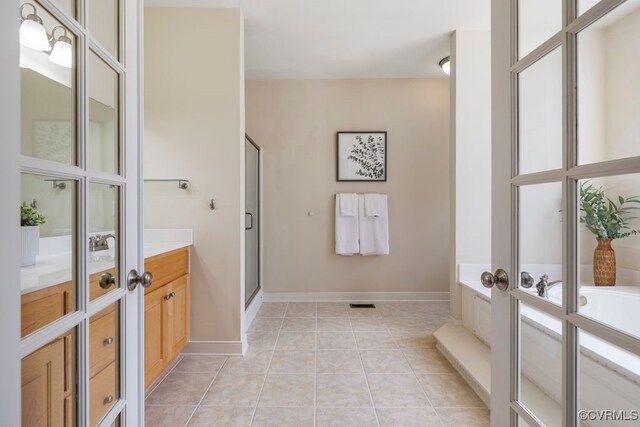 full bathroom featuring vanity, a shower stall, a bath, tile patterned flooring, and baseboards
