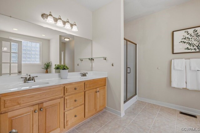 bathroom featuring a shower stall, double vanity, tile patterned floors, and baseboards