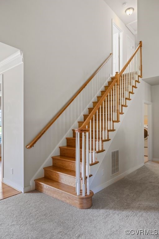 staircase featuring carpet, baseboards, and a towering ceiling
