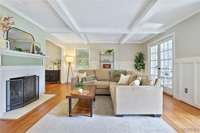 living room with wainscoting, wood finished floors, beamed ceiling, a fireplace with flush hearth, and coffered ceiling