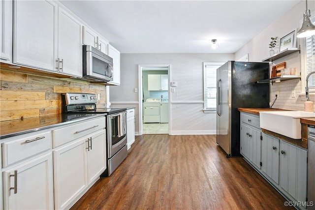 kitchen with tasteful backsplash, dark wood finished floors, a sink, separate washer and dryer, and stainless steel appliances