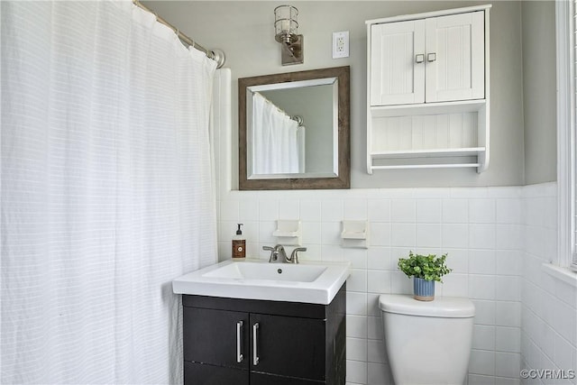 full bath with vanity, toilet, and tile walls