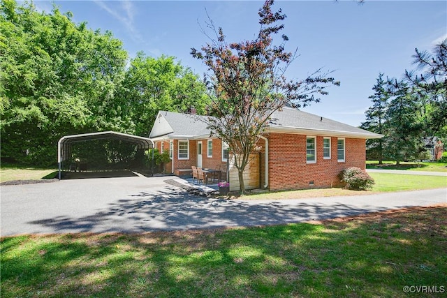 view of side of home featuring brick siding, aphalt driveway, a lawn, and a carport