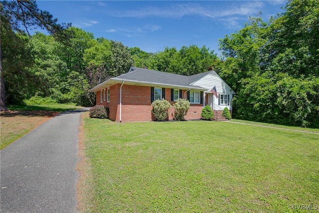 view of front of property featuring brick siding, a front lawn, and driveway