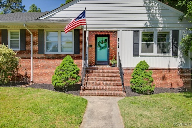 doorway to property with a yard and brick siding