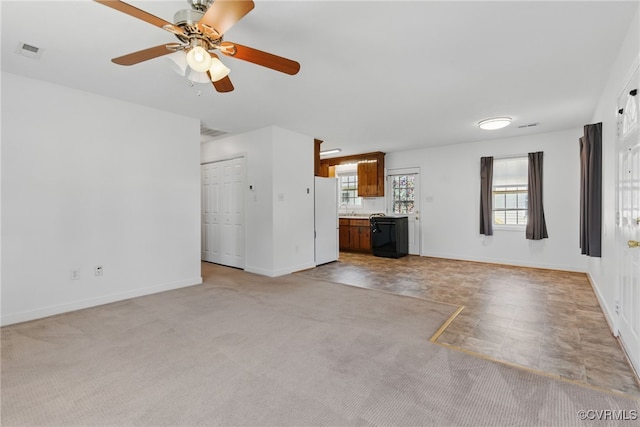 unfurnished living room featuring a ceiling fan, baseboards, visible vents, and light colored carpet