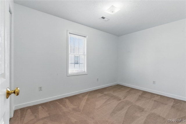 spare room with visible vents, baseboards, and light carpet