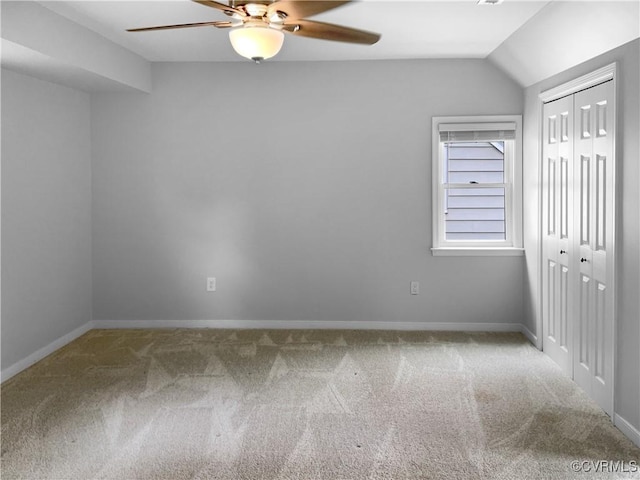 unfurnished bedroom featuring carpet floors, baseboards, lofted ceiling, and a closet