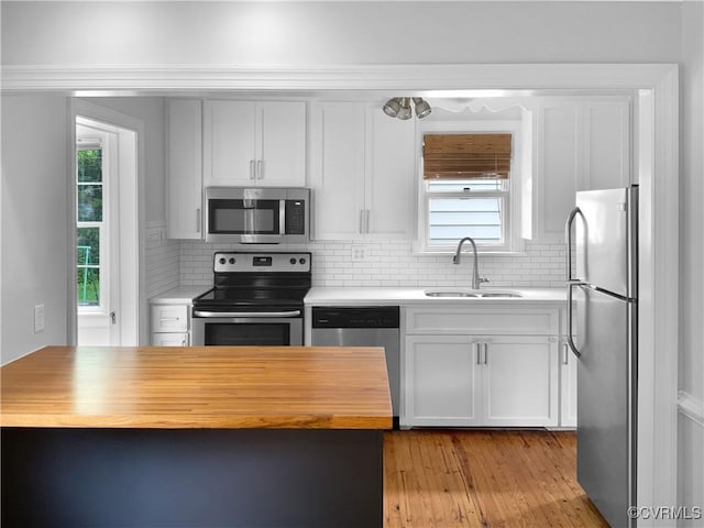 kitchen featuring decorative backsplash, wooden counters, white cabinetry, a sink, and appliances with stainless steel finishes