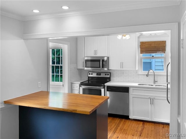 kitchen with a sink, white cabinets, stainless steel appliances, and butcher block counters