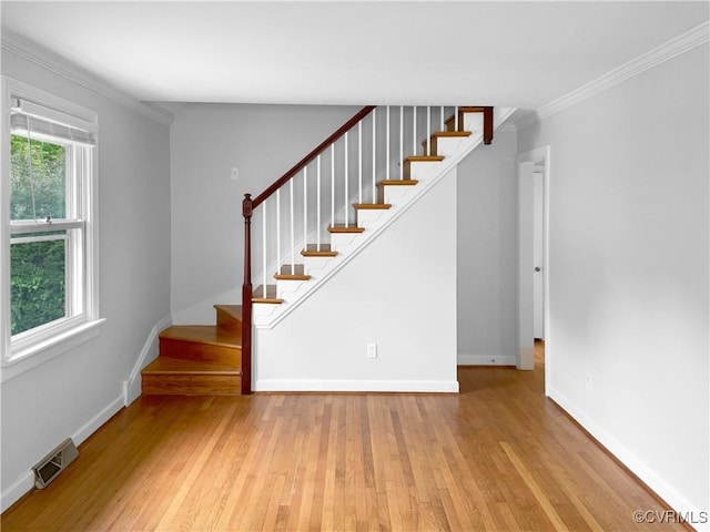 stairway with baseboards, ornamental molding, wood finished floors, and visible vents
