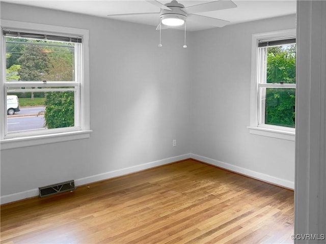 spare room featuring visible vents, a ceiling fan, light wood finished floors, and plenty of natural light