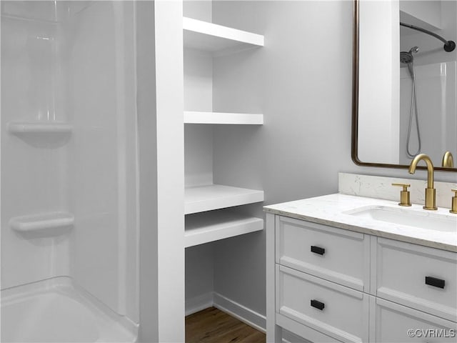 bathroom with shower / bathtub combination, baseboards, wood finished floors, and vanity