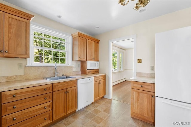 kitchen featuring a sink, a baseboard radiator, plenty of natural light, and white appliances