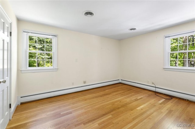 unfurnished room with visible vents, a baseboard radiator, and light wood-type flooring