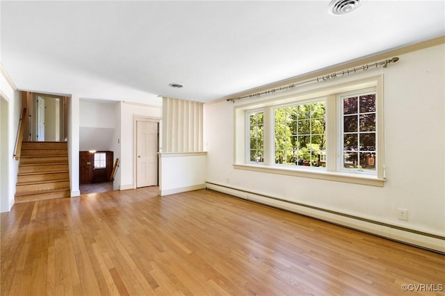 unfurnished room featuring visible vents, wood finished floors, baseboards, baseboard heating, and stairway