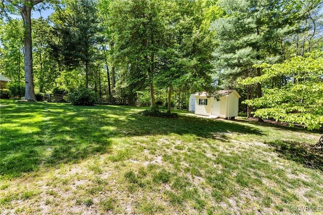 view of yard featuring a storage shed, fence, and an outdoor structure