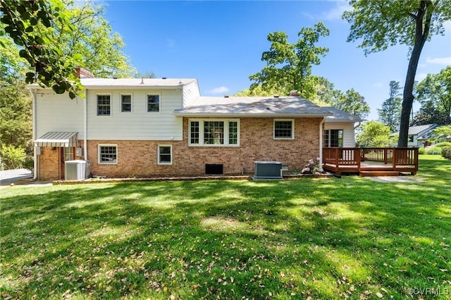 rear view of property with a chimney, a lawn, a deck, brick siding, and cooling unit