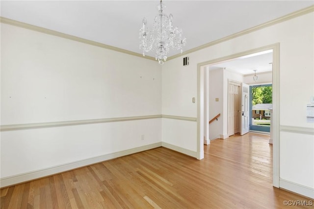 spare room with crown molding, baseboards, an inviting chandelier, and light wood finished floors