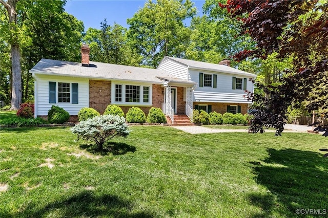 tri-level home with brick siding, a front yard, and a chimney