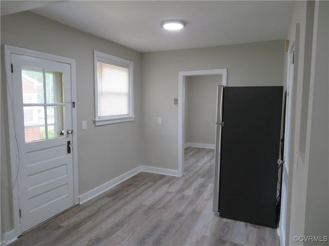interior space with baseboards, freestanding refrigerator, and light wood-style flooring