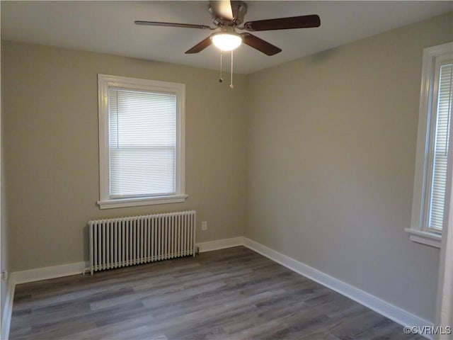 spare room with radiator, baseboards, a ceiling fan, and wood finished floors