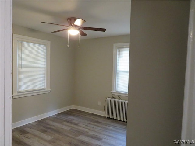 unfurnished room with radiator heating unit, baseboards, ceiling fan, and wood finished floors