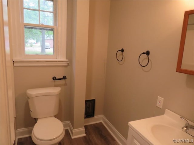 half bathroom with toilet, baseboards, wood finished floors, and vanity