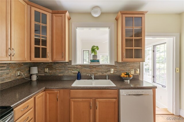 kitchen with electric range, dark countertops, tasteful backsplash, dishwasher, and a sink