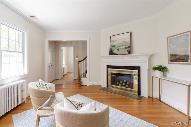 living area featuring crown molding, radiator heating unit, stairs, wood finished floors, and visible vents