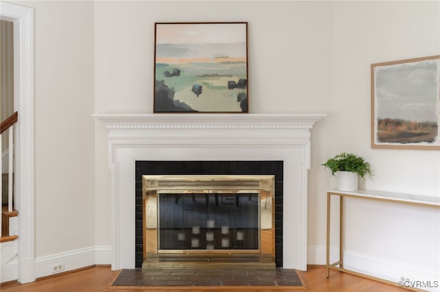 details with baseboards, a fireplace with flush hearth, and wood finished floors