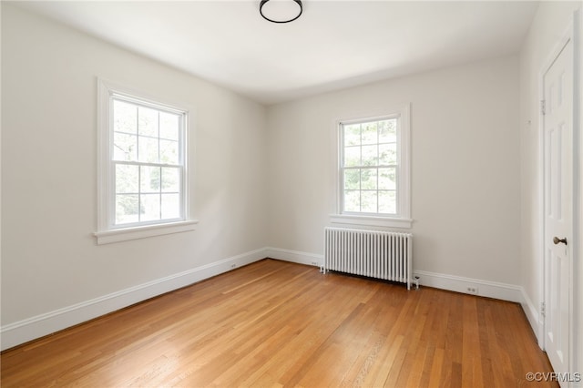 unfurnished bedroom featuring radiator heating unit, baseboards, and light wood-style floors