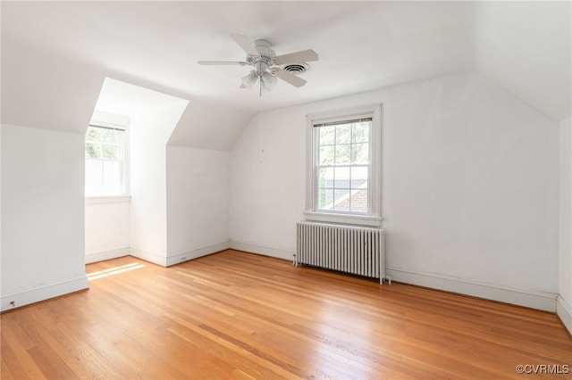 bonus room featuring light wood-style flooring, a healthy amount of sunlight, radiator heating unit, and lofted ceiling