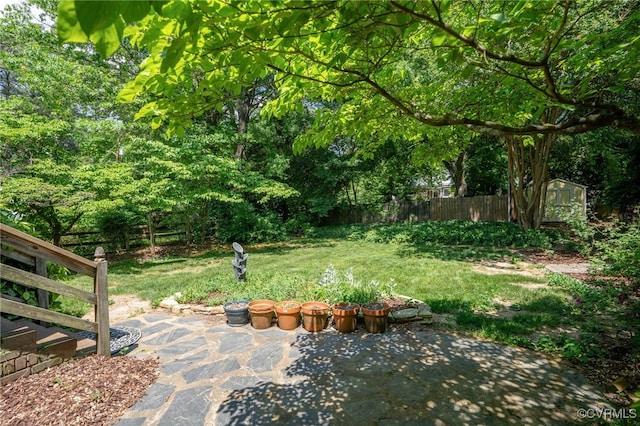 view of yard featuring a storage unit, an outdoor structure, a patio area, and fence