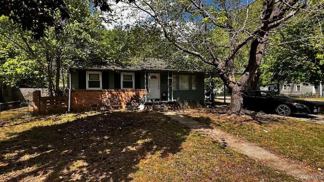 bungalow-style house featuring brick siding and fence