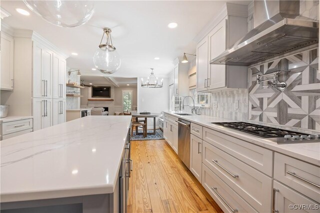 kitchen with wall chimney range hood, a sink, stainless steel appliances, recessed lighting, and light wood-type flooring