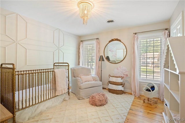 bedroom with an inviting chandelier, multiple windows, hardwood / wood-style floors, and visible vents