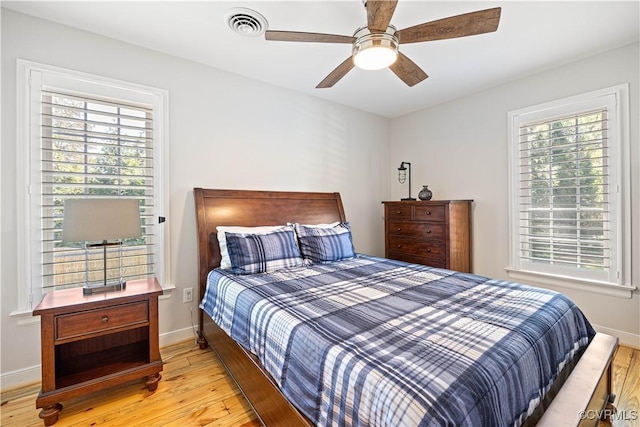 bedroom with visible vents, baseboards, ceiling fan, and hardwood / wood-style floors
