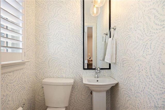half bathroom with toilet and wallpapered walls